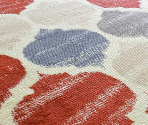 Close-up of colorful geometric rug with red, blue, and beige patterns.