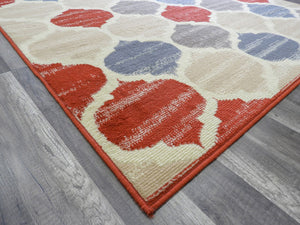 Corner of a colorful geometric patterned rug on wooden floor.