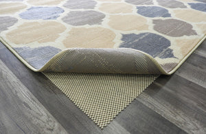 Close-up of abstract rug with beige, brown, and blue patterns, showing non-slip backing on a hardwood floor. Ideal for modern homes.