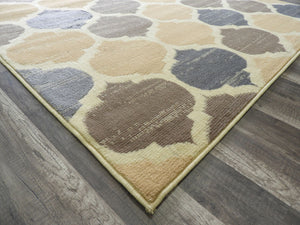 Corner view of abstract rug with beige, brown, and blue patterns on hardwood floor. Perfect for adding a modern touch to any room.