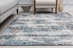 Close-up of an abstract rug with distressed blue, white, and beige patterns in a modern living room, enhancing contemporary decor.