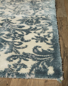 Close-up of the corner of a blue and white floral area rug, highlighting its intricate design and texture.