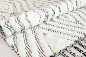 Rolled-up white and black geometric pattern rug showing texture and design.