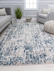 Contemporary living room with a grey sofa, a white armchair, a cream and blue abstract rug, and a large potted plant