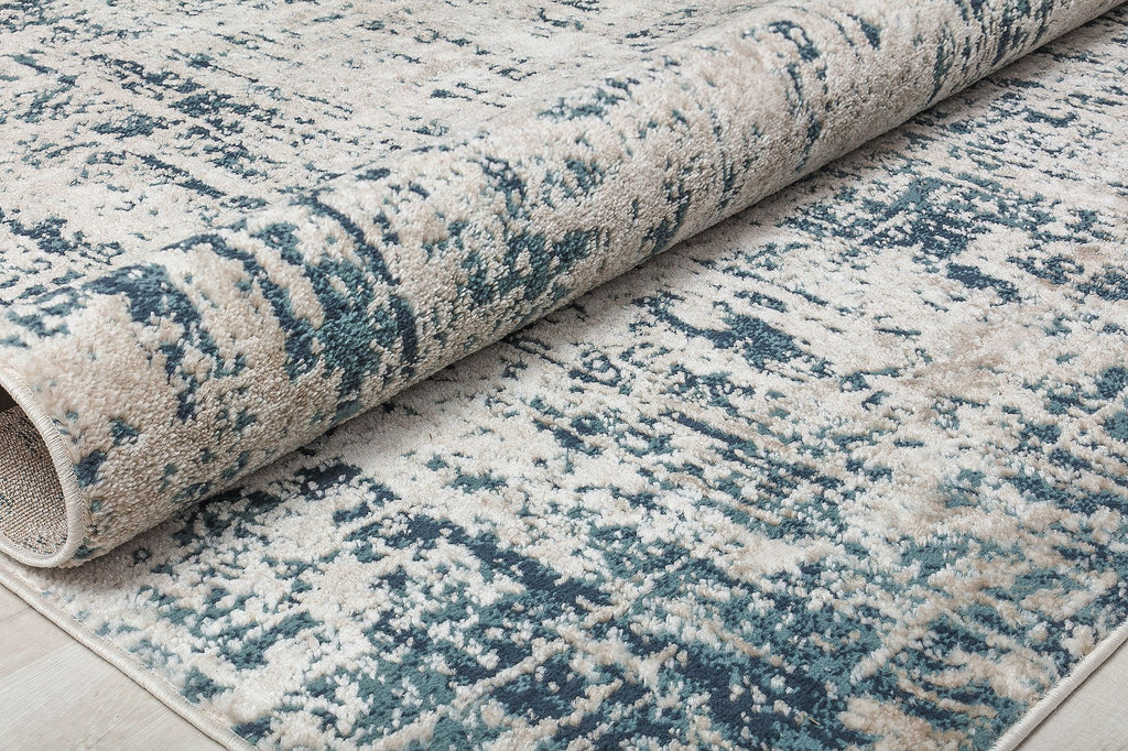 Rolled-up rug with a distressed blue and white pattern, showcasing its durability and modern design for contemporary spaces.