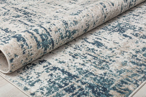 Rolled-up rug with a distressed blue and white pattern, showcasing its durability and modern design for contemporary spaces.