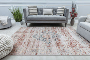 Vintage-style rug with distressed red and beige pattern in a modern living room, featuring a grey sofa and accent pillows.