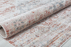 Close-up of a rolled vintage-style rug with distressed red and beige pattern, highlighting texture and craftsmanship.