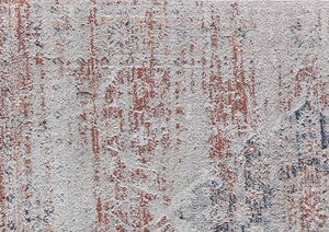 Close-up of vintage-style rug with distressed red and beige patterns, highlighting intricate design details and texture.