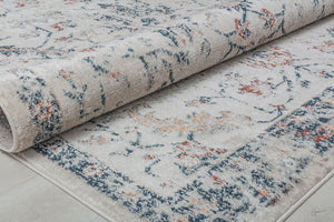 Close-up of vintage-style rug rolled up, showcasing intricate floral patterns in blue, beige, and rust, ideal for classic home decor.