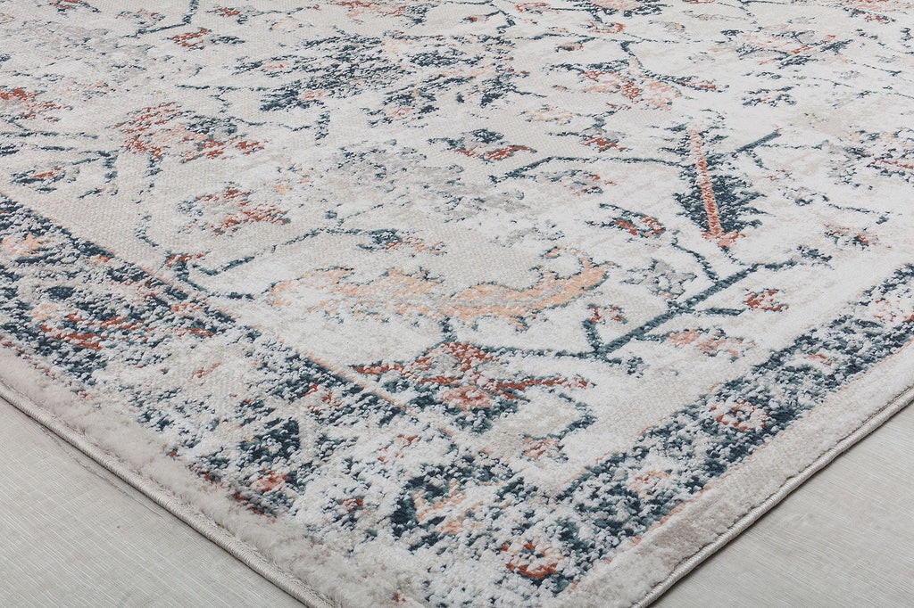 Close-up of the corner of a vintage-style rug, featuring intricate floral patterns in blue, beige, and rust, adding classic elegance to any decor.