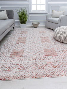 Minimalist living room with a white and red patterned rug, gray sofa, white armchair, and green plant adding a fresh touch