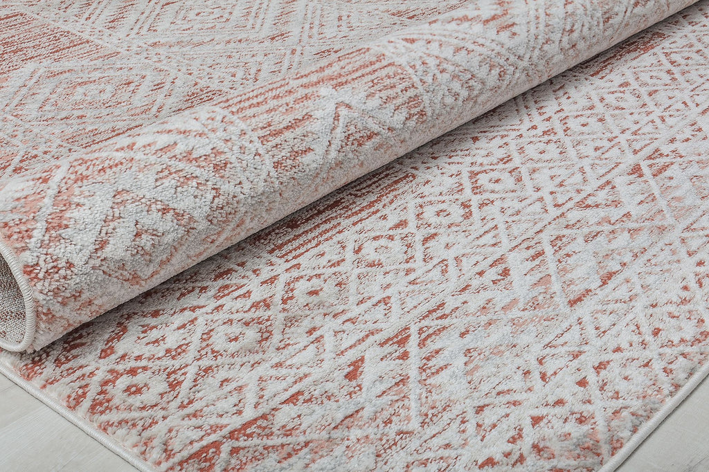 Close-up view of a rolled red and white geometric pattern rug, highlighting the texture and design.