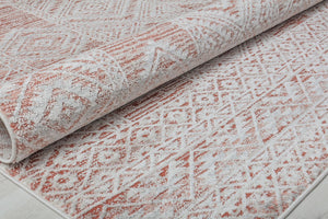 Close-up view of a rolled red and white geometric pattern rug, highlighting the texture and design.