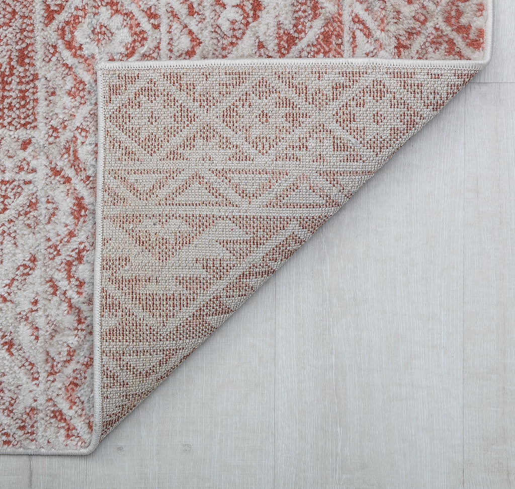 Close-up of the corner of a red and white geometric pattern rug, showing the underside.