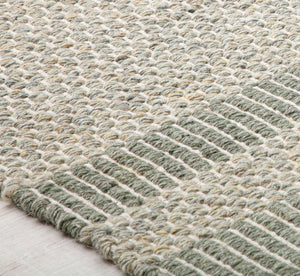 Close-up of a green woven rug's texture with striped detail, highlighting the craftsmanship and material quality for a modern look.