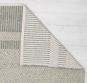 Close-up of a green woven rug's corner flipped to show the detailed weave and striped backing, emphasizing the quality and design.