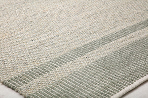 Close-up of a green and beige woven rug showcasing its detailed texture and subtle stripe pattern, perfect for home decor.