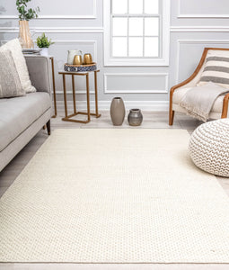 Cozy living room with a light gray sofa, neutral rug, wooden armchair, side table with decor, and decorative vases on the floor