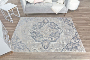 Overhead view of a gray and white traditional pattern rug placed in a living room with a gray sofa.