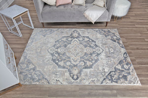 Overhead view of a gray and white traditional pattern rug in a living room with a gray sofa.