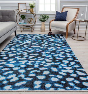 Modern abstract rug with a blue and black pattern in a stylish living room featuring a gray sofa, wooden chair, and decorative accents.