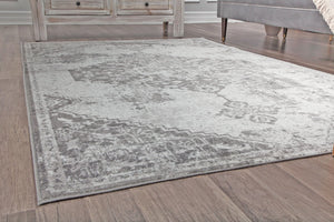 Gray vintage rug with distressed patterns, displayed on a wooden floor, adding a touch of elegance and style to any room decor.