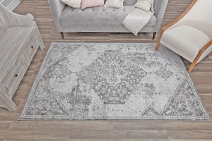 Top view of a gray distressed rug in a living room setting, highlighting its intricate vintage-inspired pattern on wooden flooring.