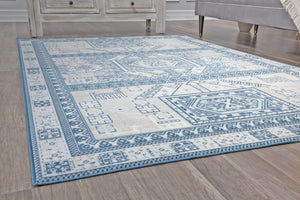 Side view of a beige and blue geometric patterned rug on wooden flooring, enhancing the room's modern decor.