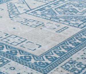 Detailed view of a beige and blue rug with geometric patterns, showcasing the texture and intricate design elements.