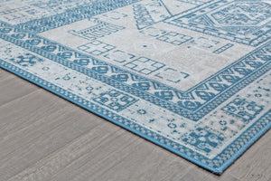 Close-up of the edge of a beige and blue rug with geometric patterns, highlighting the detailed border design and texture.