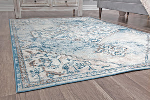 Close-up angle of a blue and gray distressed rug with a central medallion, perfect for adding a vintage touch to your decor.