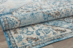 Side view of a folded blue and gray distressed rug, highlighting its intricate vintage design and durable material.