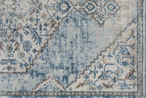 Close-up of the corner design of a blue and gray distressed rug, showcasing intricate floral patterns and vintage aesthetics.