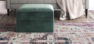 Antique rose area rug with intricate patterns under a green ottoman.