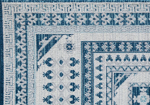 Close-up of the corner of a blue and white geometric patterned rug with intricate floral and border designs