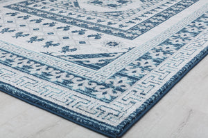 Close-up of the edge of a blue and white geometric patterned rug showing intricate floral and border details.