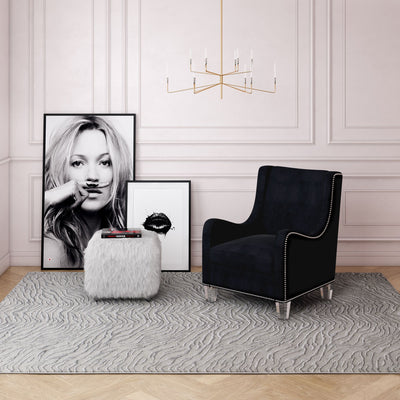 Modern reading nook with a black armchair, white textured rug, and stylish artwork.