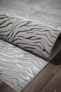 Close-up of a rolled white textured rug with a wave-like pattern.