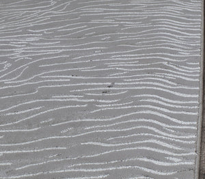 Top view of a white textured rug with wave-like patterns.