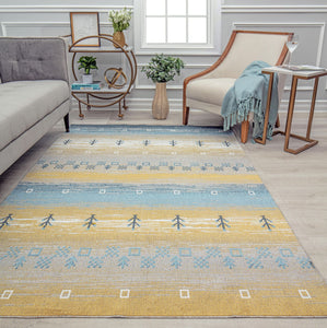 Stylish living room with a grey sofa, a white armchair, a blue and yellow patterned rug, and decorative plants and tables