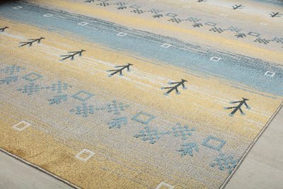 Close-up of rug with blue and beige geometric patterns and tree motifs, adding a natural and stylish touch to any room.