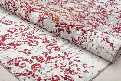 Rolled-up vintage-style rug with intricate red floral patterns on a beige background, perfect for adding a classic touch to any decor.