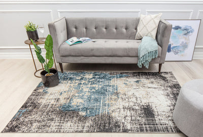 Living room with a modern sofa and a rug featuring a distressed blue and beige pattern, adding an artistic touch to the decor.
