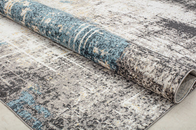 Rolled-up rug with a distressed blue and beige pattern, showcasing its artistic design and durability for contemporary home decor.