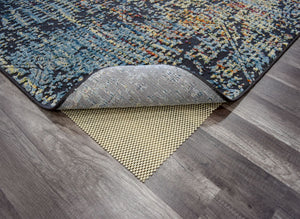 Corner of an abstract rug with a non-slip pad on a wooden floor.