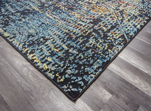 Corner of an abstract rug showcasing blue and yellow patterns on a dark background, laid on a wooden floor.