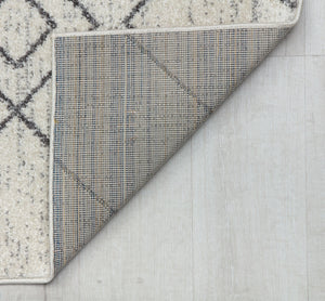 Close-up of the corner of a beige rug with a geometric pattern, showcasing the underside and the detailed stitching.