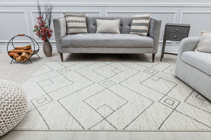 Living room setup with a beige rug featuring a geometric pattern, placed in front of a gray sofa and armchair.