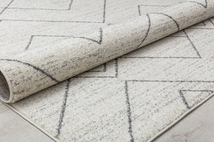 Beige rug with a geometric pattern, partially rolled to show texture and thickness, perfect for modern living spaces.